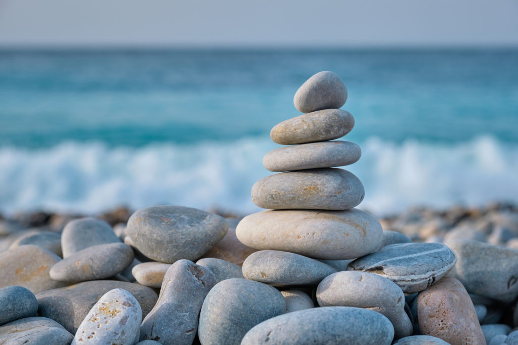 Zen meditation relaxation concept background - balanced stones stack close up on sea beach in st. pete. Therapy in St. Petersburg, FL and online therapy in florida can help you heal.