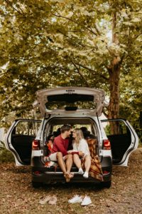 Couple cuddling in the back of their SUV in the woods, looking longingly at each other after online couples therapy in Florida from a St. Pete Couples therapist. You can get Quarantine Friendly Date Ideas from a St. Pete Couples Therapist here!