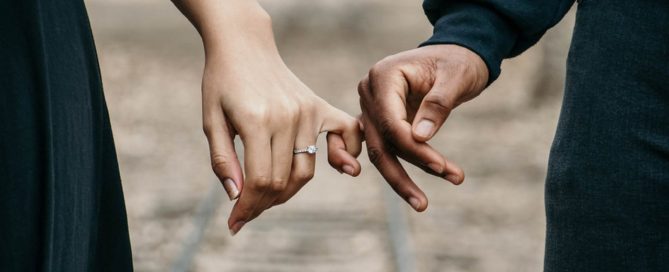 Two hands holding pinkies, one with an engagement ring. Premarital Counseling sets a solid foundation for your life.