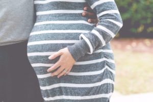 Pregnant woman being held by partner for photo. Maternal mental health in St. Petersburg, FL matters! Get help during pregnancy with ME-Therapy St. Pete therapists and online therapy in Florida.