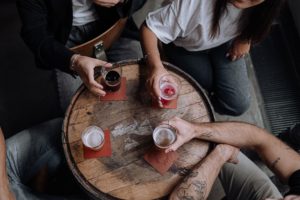 People sitting around a small wooden table with alcohol. Therapists in St. Petersburg, FL can help deal with dependency. Anxiety treatment in St. Pete is available via online therapy in Florida for marriage counseling, maternal mental health, relationship therapy and more.