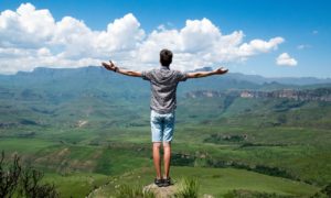 Arms wide open for therapy in St. Pete. Man stands overlooking the rolling hills in the bright daylight after online therapy in Florida helped him.