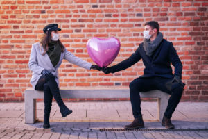 Couple on bench holding heart balloon with masks on. Online couples therapy in Florida with a St. Pete couples therapist. Relationship therapy or marriage counseling in St. Pete can help you here!