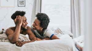 Happy couple in bed smiling. A St. Pete therapist can help with couples therapy or marriage counseling in st. Petersburg, FL here!