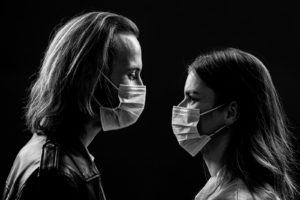 Couple wearing masks, facing each other with a black and white background. Get online couples therapy in Florida with a St. Pete couples therapy or marriage counseling in St. Petersburg, FL here.