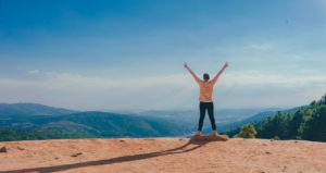 Standing on a mountaintop with hands up to celebrate. Trauma Therapy in St. Petersburg, FL can help you with online couples therapy in florida too.