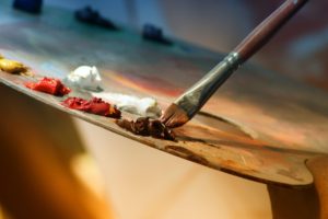 Paint brush and paints on a palette depicting preparation for art therapy in St. Petersburg, FL. You can get online therapy in Florida here to support your healing with art therapy in St. Pete too.
